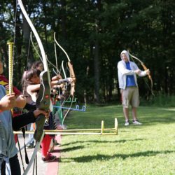 Kids learning to shoot arrows with bows